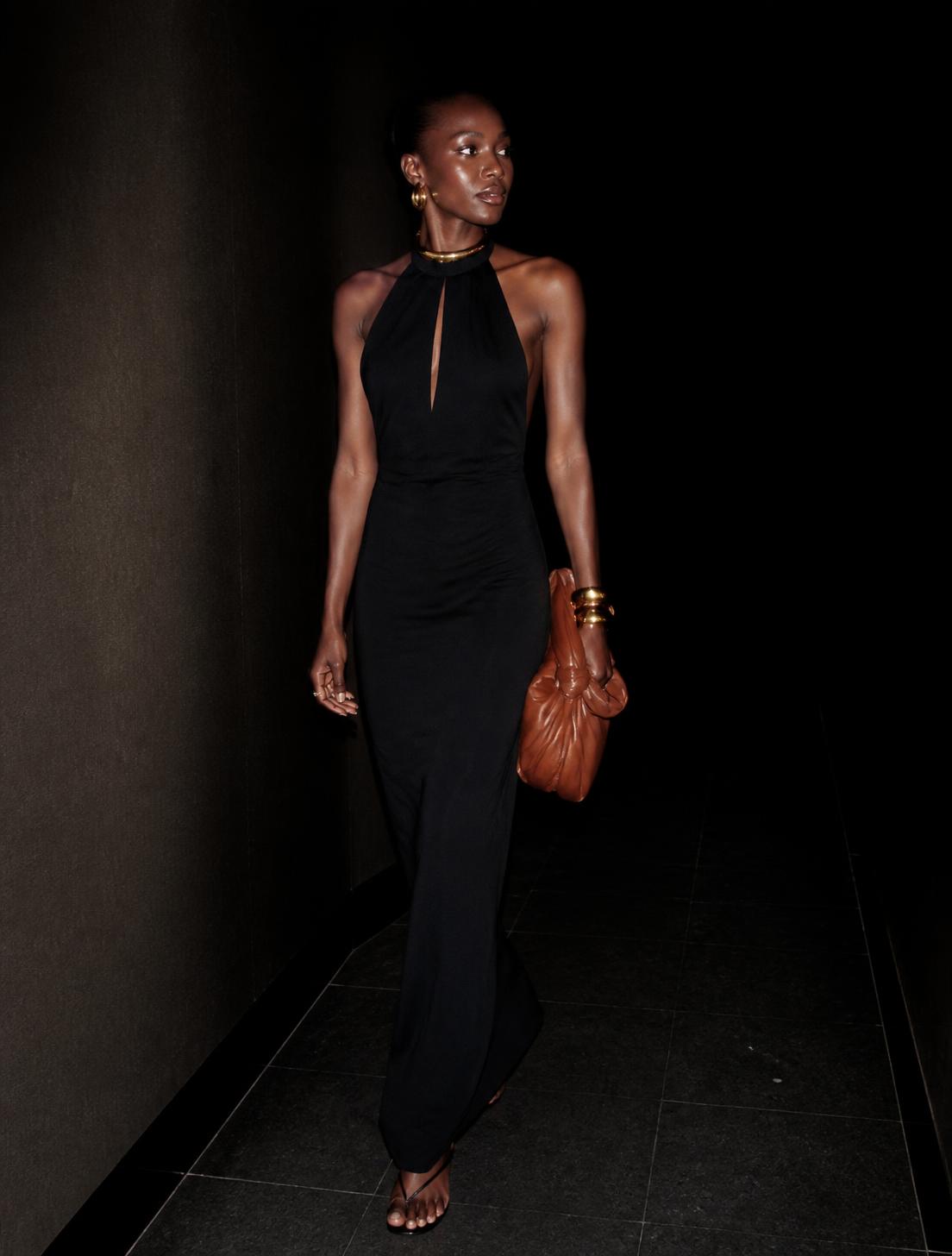NiCalé in a black column dress with gold hardware, direct flash
